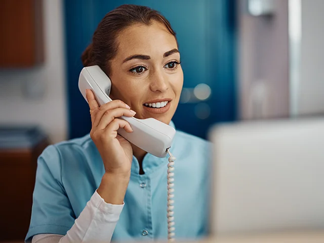 Terminvereinbarung: Patientin telefoniert mit der Zahnarztpraxis