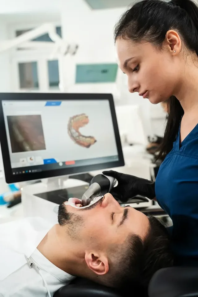 Zahnmedizinische Fachangestellte nimmt mit dem Intraoralscanner einen digitalen Abdruck, der Scan erscheint live auf dem Bildschirm
