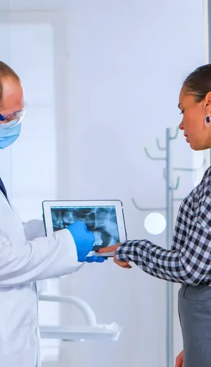 Roentgenaufnahme gemeinsam ansehen Zahnarzt und Patientin betrachten gemeinsam eine Röntgenaufnahme auf dem Tablet